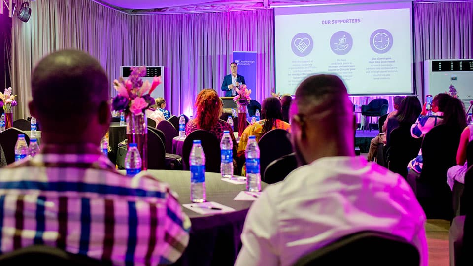 : A shot of alumni from the back of a room looking at the panelists at an alumni reception in Lagos hosted by the University.